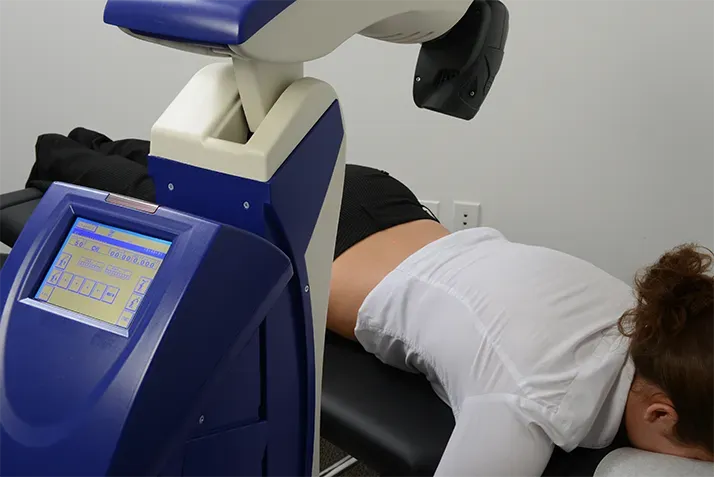 Laser therapy machine delivering treatment while a patient lies on a clinical table.
